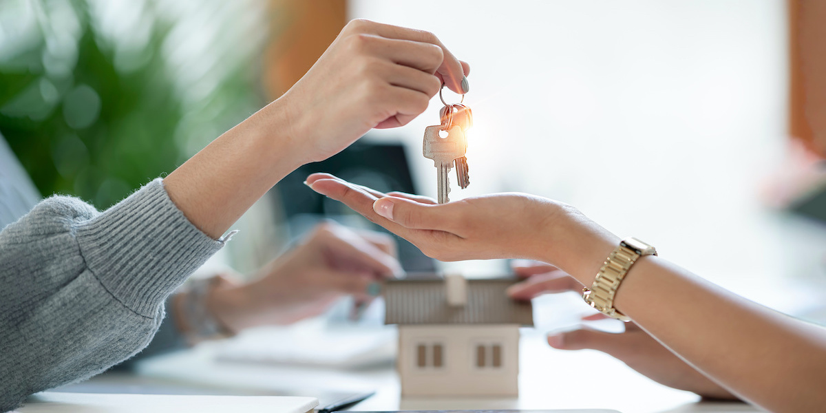 Der Immobilienmakler händigt die Schlüssel der Wohnung an den künftigen Besitzer aus.