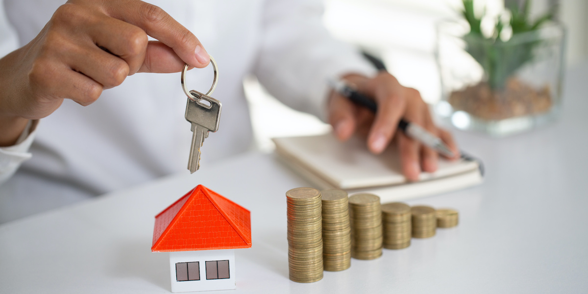 "Ein Immobilienmakler hält ein Hausmodell und Schlüssel in der Hand, um eine Immobilieninvestition zu symbolisieren, während im Hintergrund die Kaufnebenkosten beim Immobilienkauf dargestellt werden."